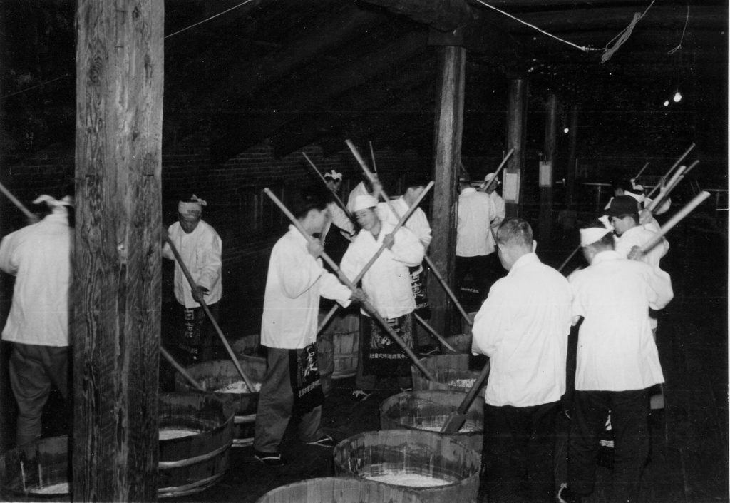 1960 年辰馬本家酒造的山卸（酛摺り）作業，多名藏人手持長棒在酛桶中作業