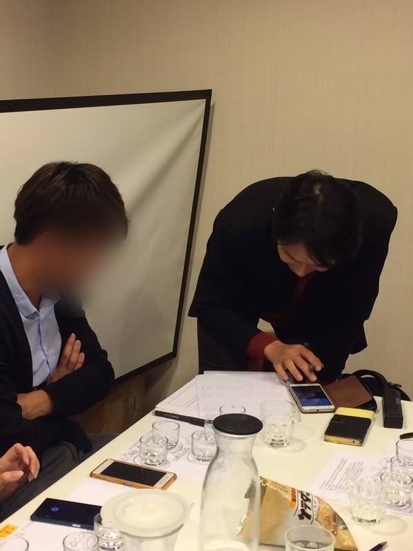 講者俯身與參加者確認手機上的內容